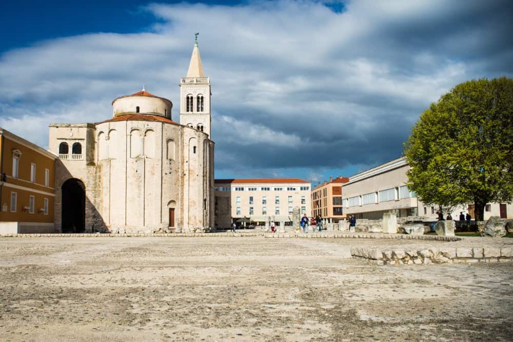 Eine Kirche mit einem Uhrturm in der Mitte eines Platzes, bekannt als eine der Sehenswürdigkeiten in Zadar.
